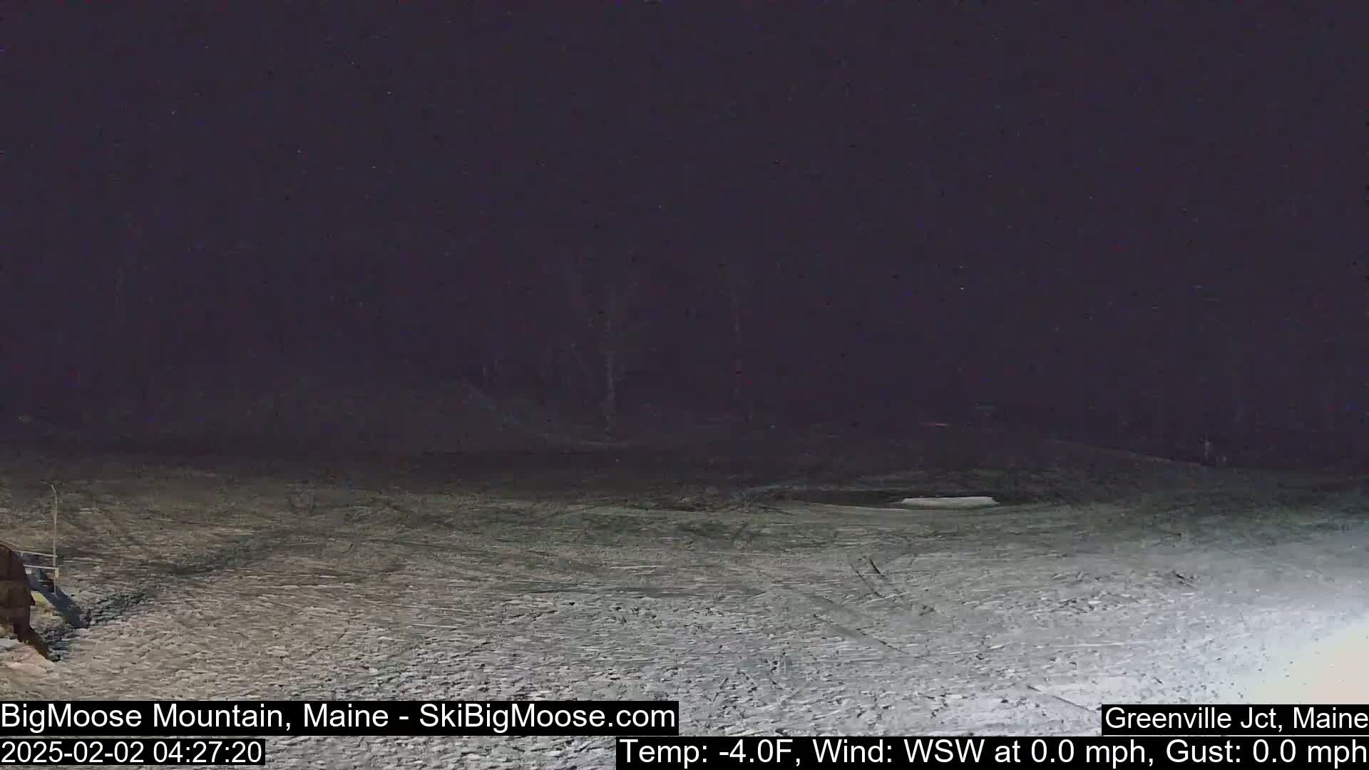 A snow-covered slope is visible at night under a dark sky with calm weather conditions.