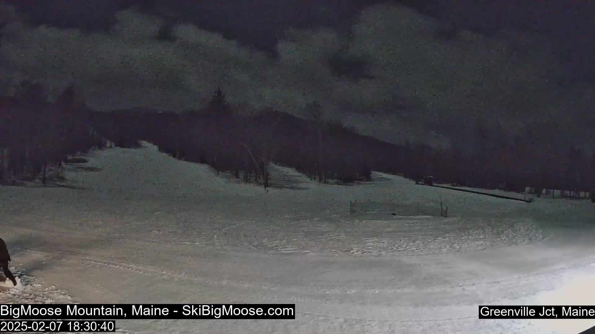 A snow-covered ski slope at night under a dark, cloudy sky.
