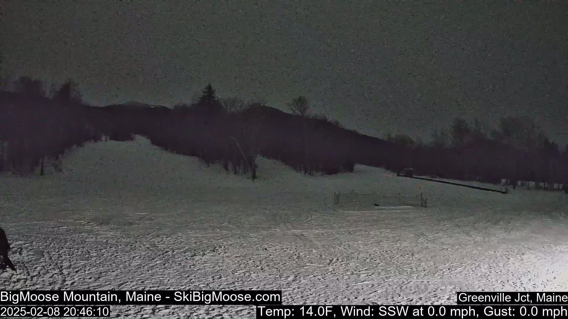 A snow-covered ski slope at night under a dark sky.