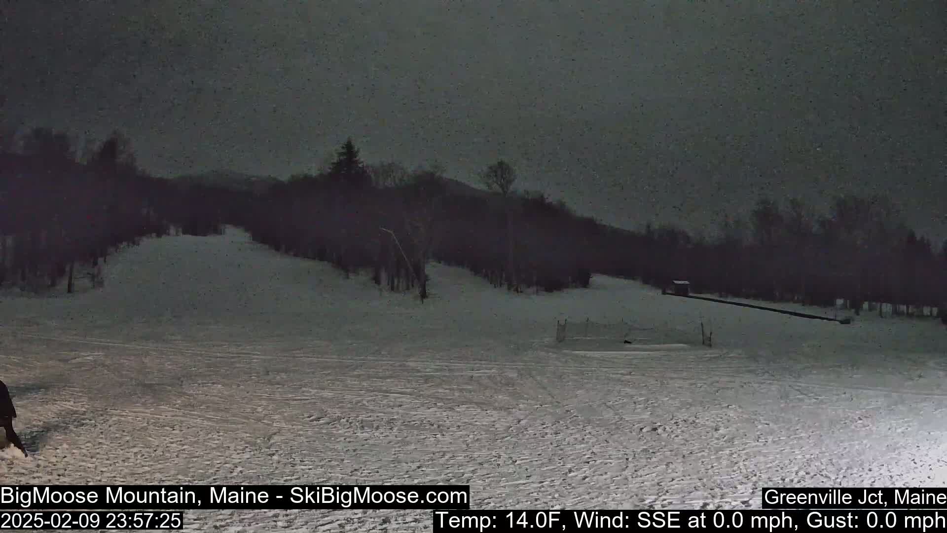 A snow-covered ski slope at night under a dark, cloudy sky.