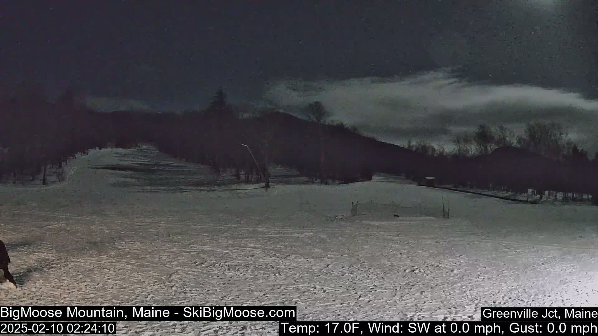 A snow-covered ski slope at night under a dark, cloudy sky.