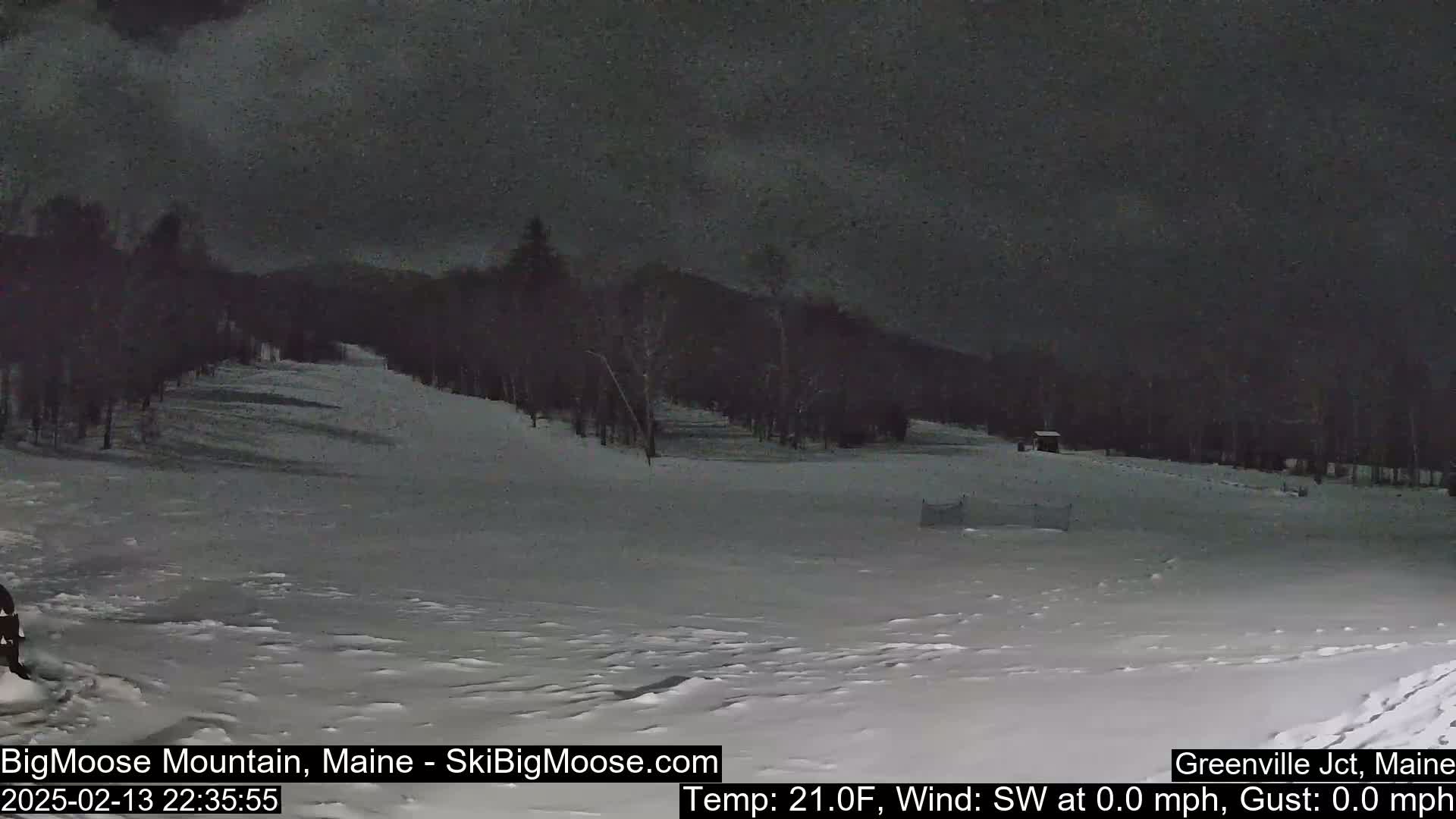 A snow-covered ski slope at night under a dark sky.