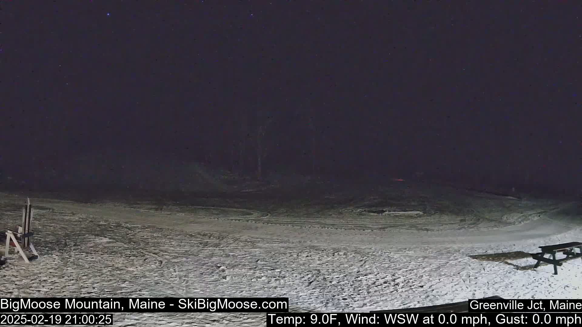 A snow-covered ski slope is visible under a dark, clear night sky with a few stars.