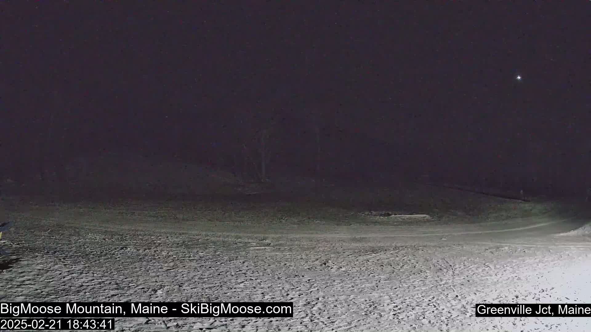 A snow-covered landscape is visible at night under a clear, dark sky.