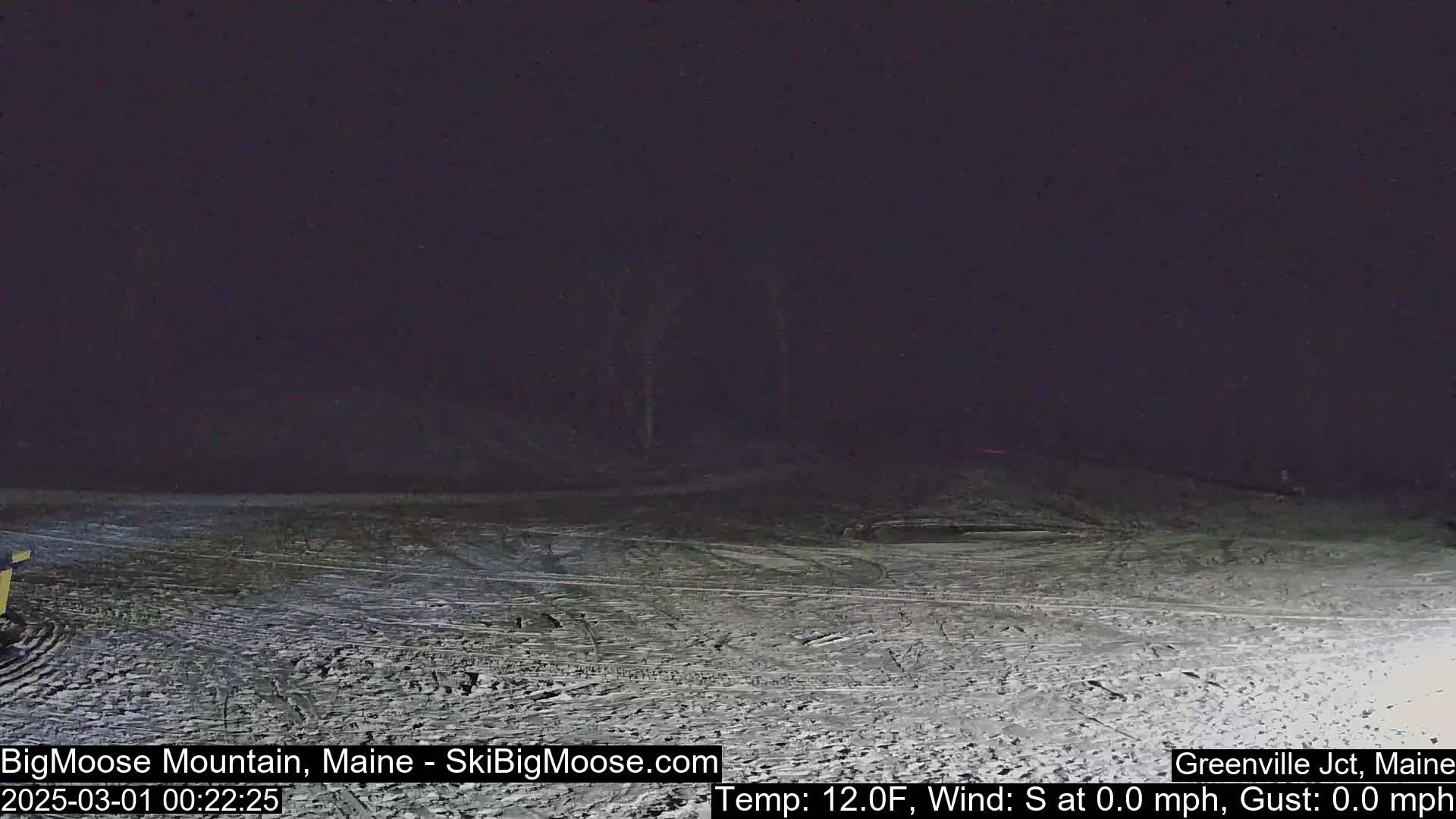 A snow-covered, dark landscape is visible at night with a temperature of 12 degrees Fahrenheit and calm winds.