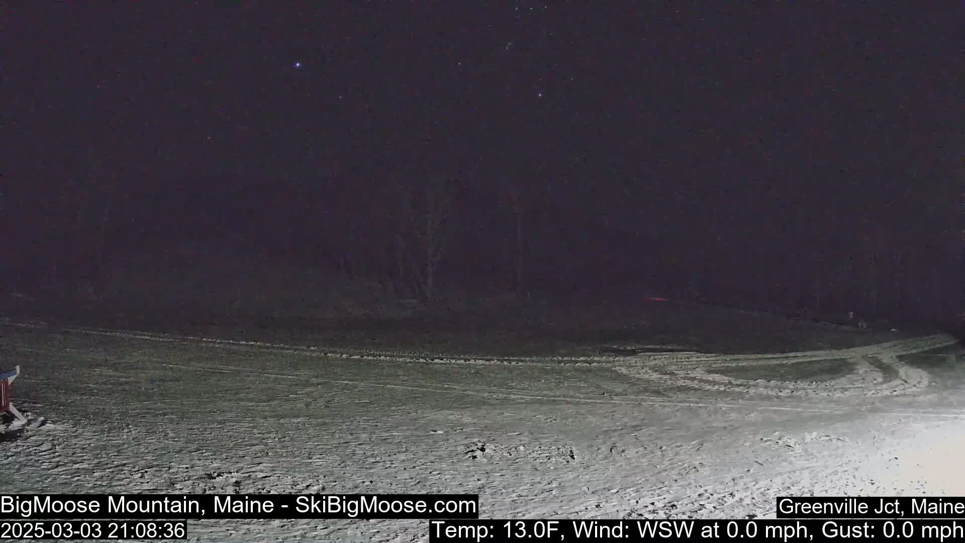 A snow-covered, dark landscape is visible under a clear, starry night sky.