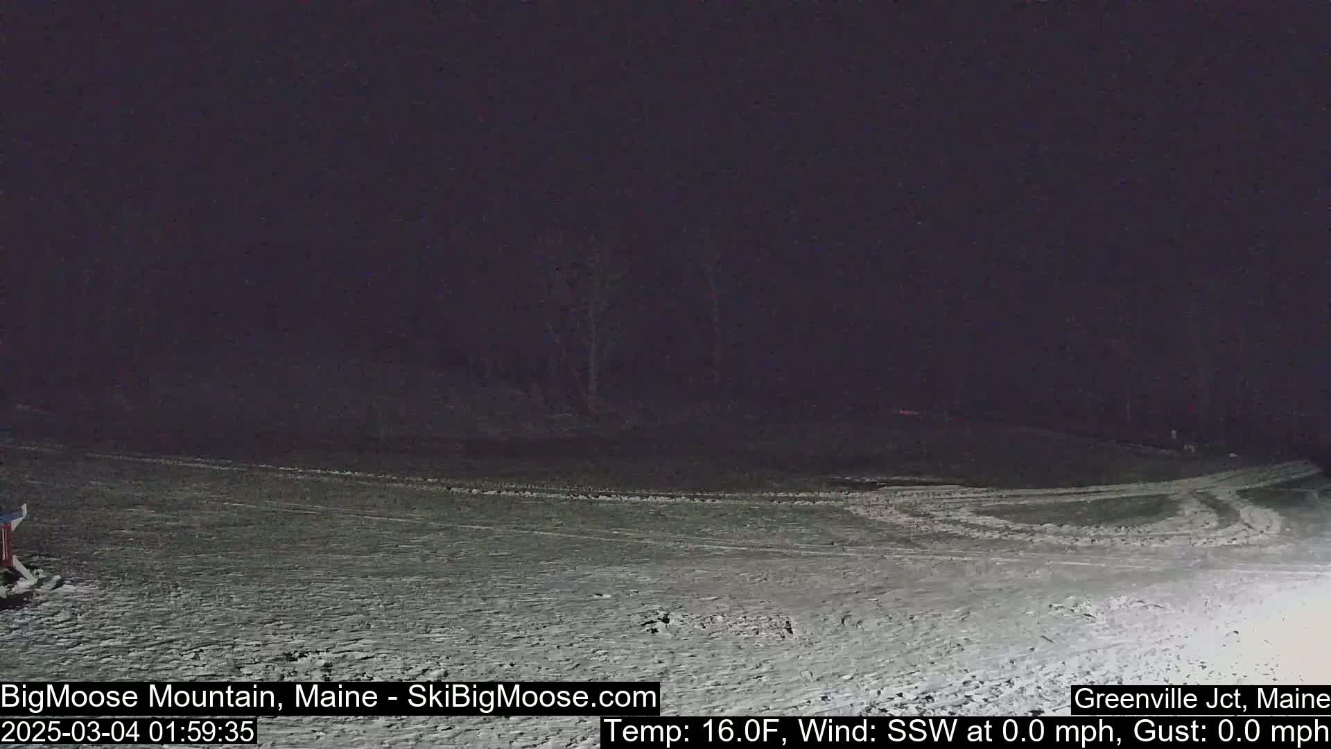 A snow-covered landscape is visible at night under a dark sky, with calm conditions.