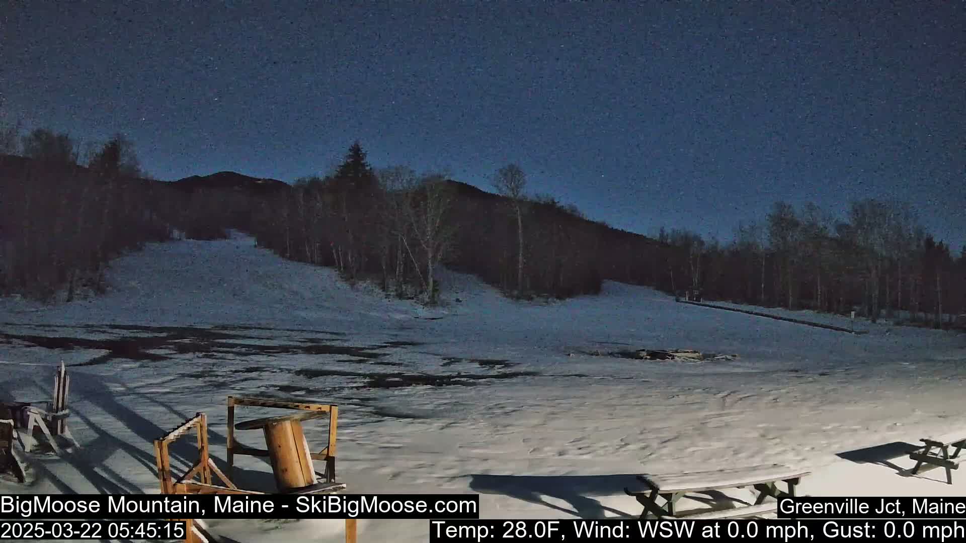 A snow-covered ski slope at night under a dark, starry sky.