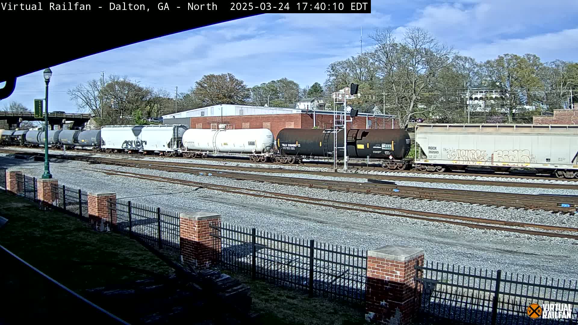 A long freight train sits on a railway track under a partly cloudy sky.