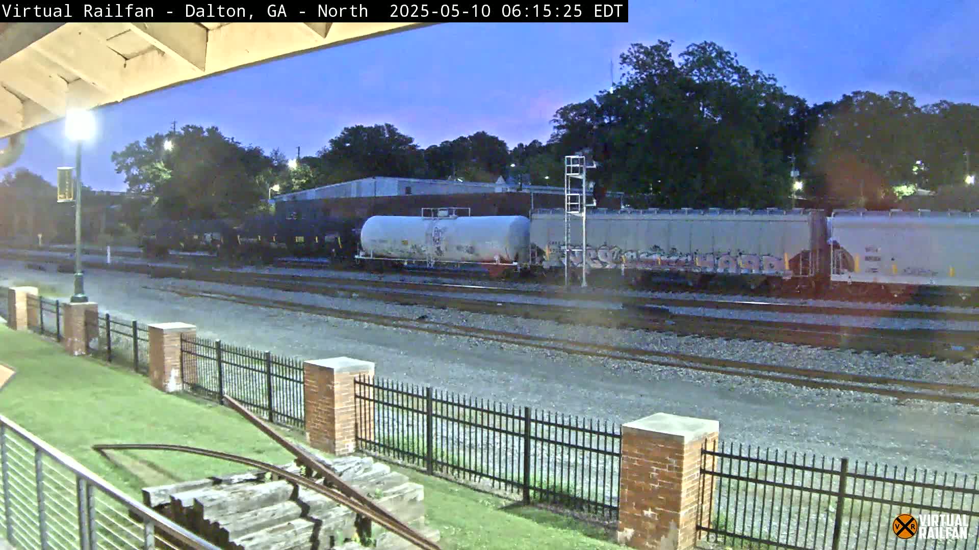 A freight train passes by at twilight, under a mostly clear sky.