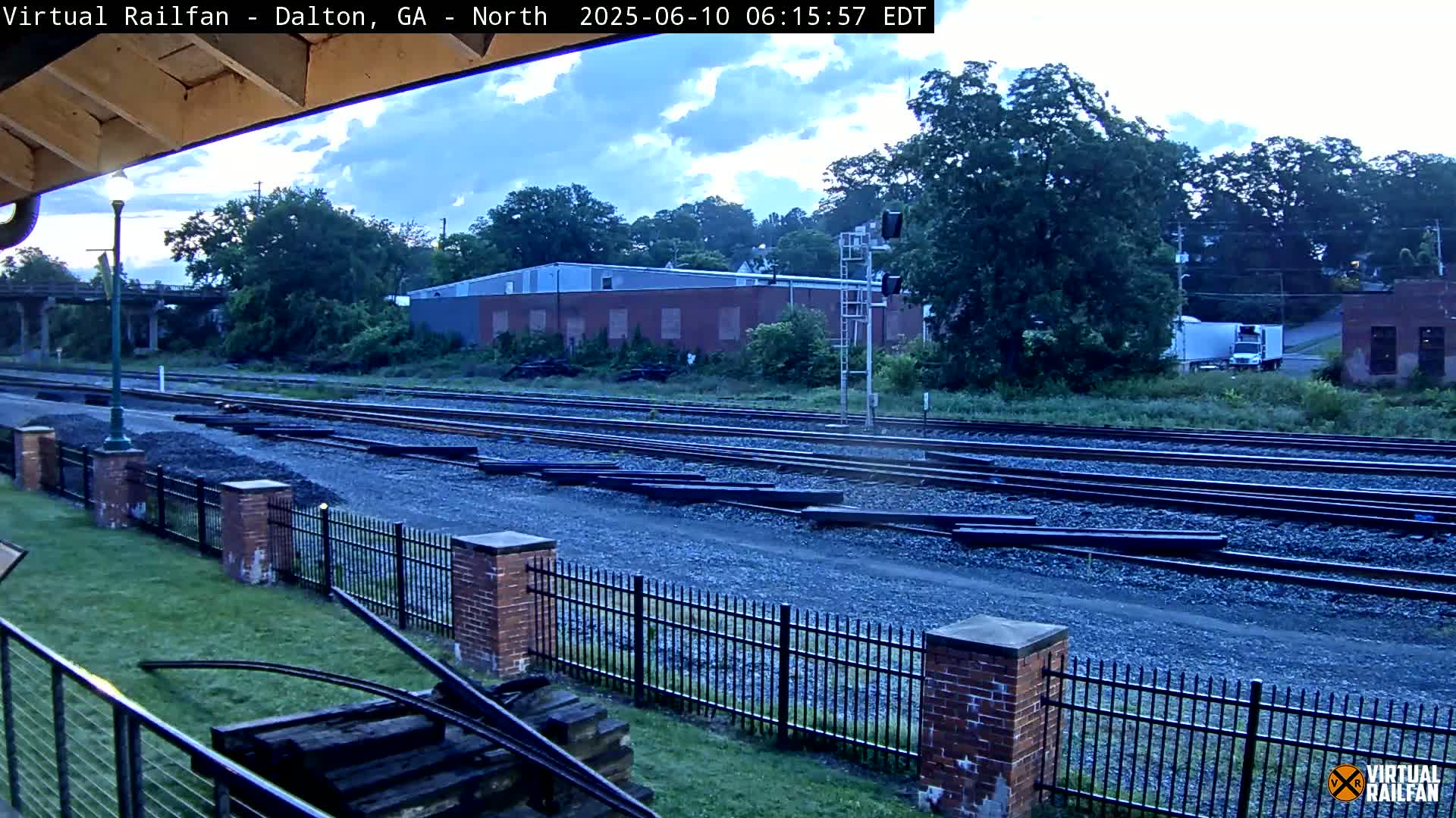A view of railroad tracks and a nearby industrial building under an overcast sky.