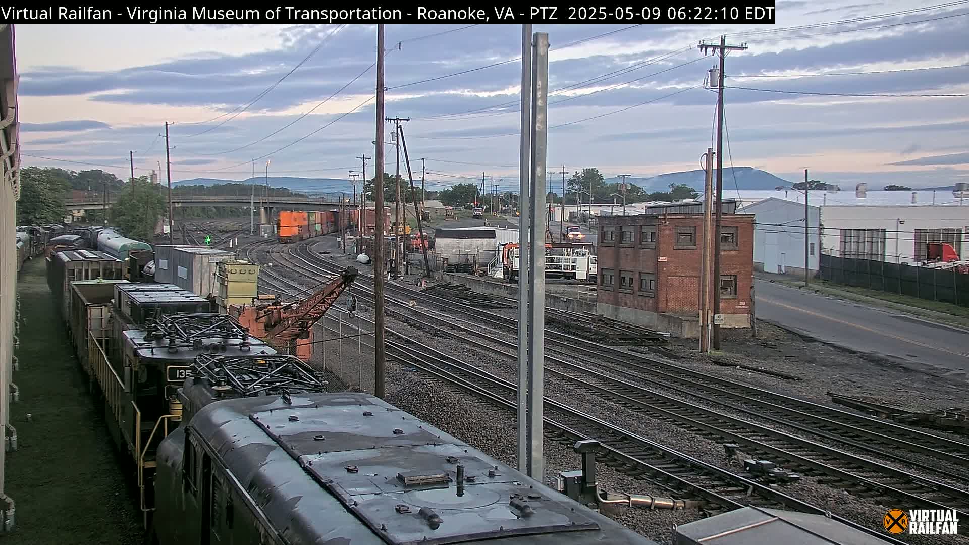 A train yard with multiple railway tracks and freight cars under a partly cloudy sky.