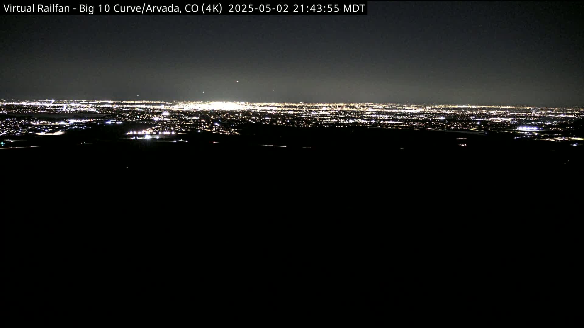 A nighttime, long-range view of a city's lights spread across a dark landscape.