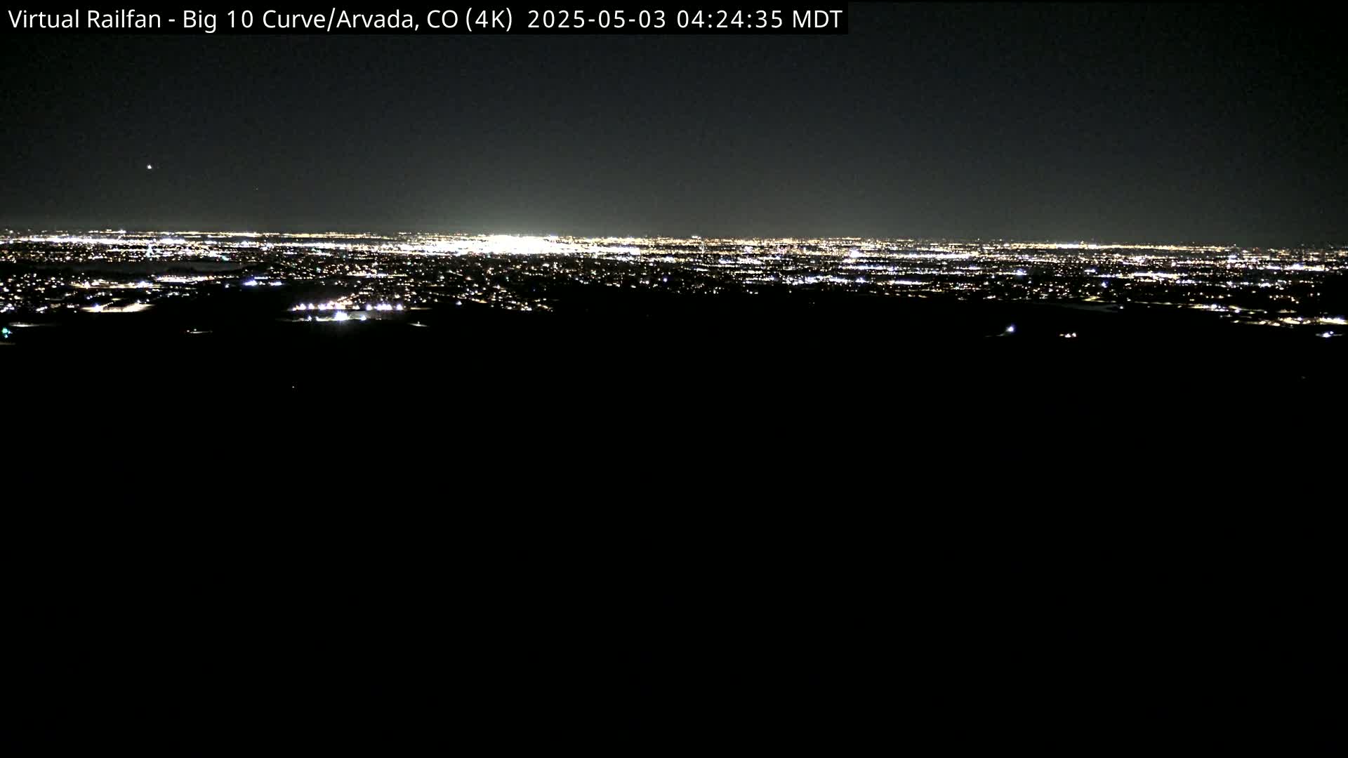 A distant city skyline glows with lights at night under a dark sky.