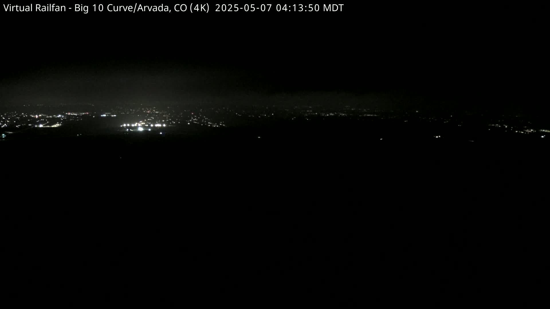 A nighttime, long-distance view of a city's lights spread across a dark landscape.