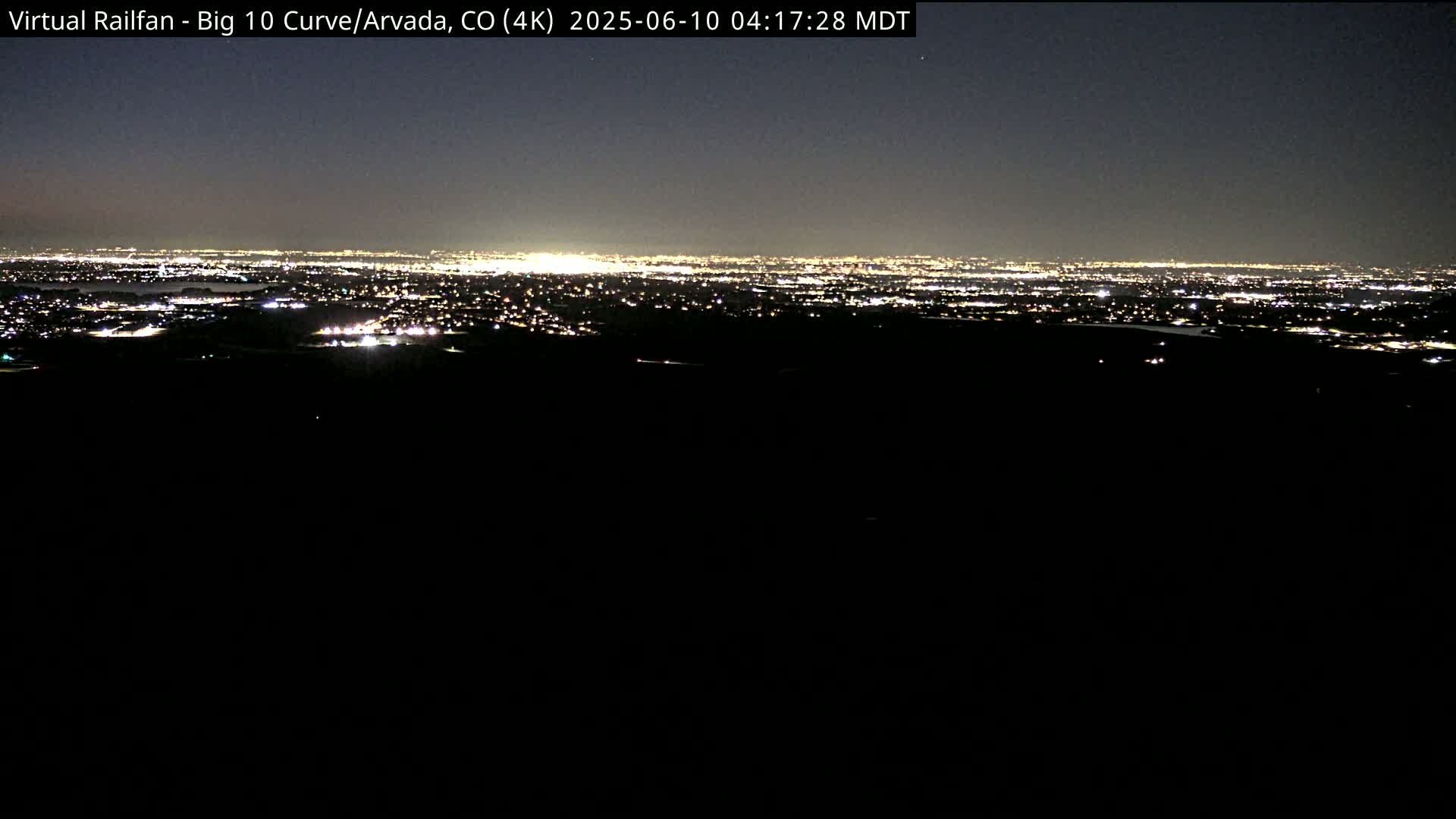 A distant city skyline is illuminated at night under a dark sky.