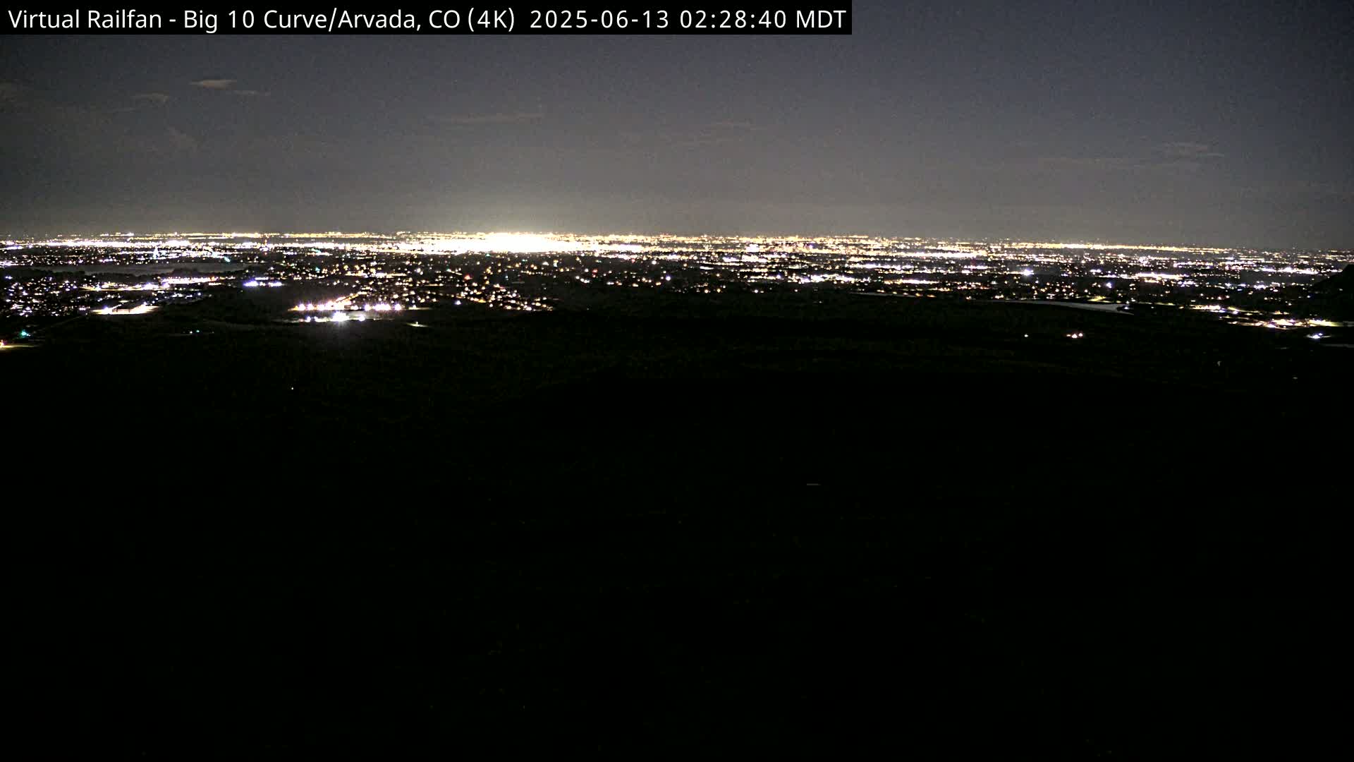 A nighttime, long-range view of a city's lights spread across a dark landscape.