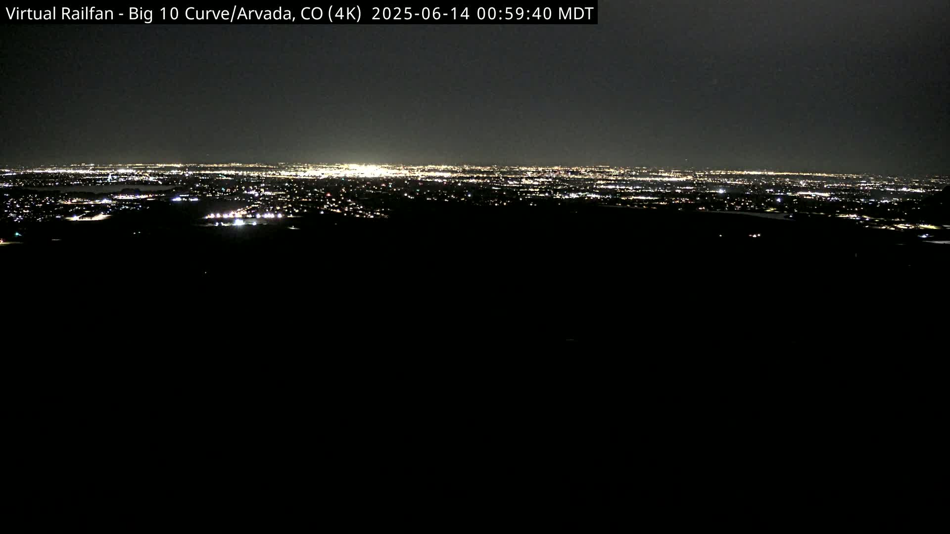 A nighttime, long-distance view of a city's lights spread across a dark landscape.