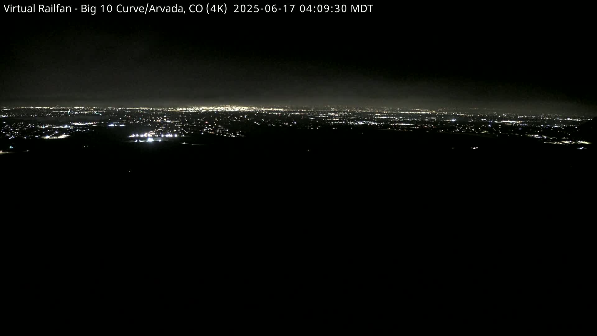 A nighttime, hazy view of a distant city skyline illuminated by numerous lights.