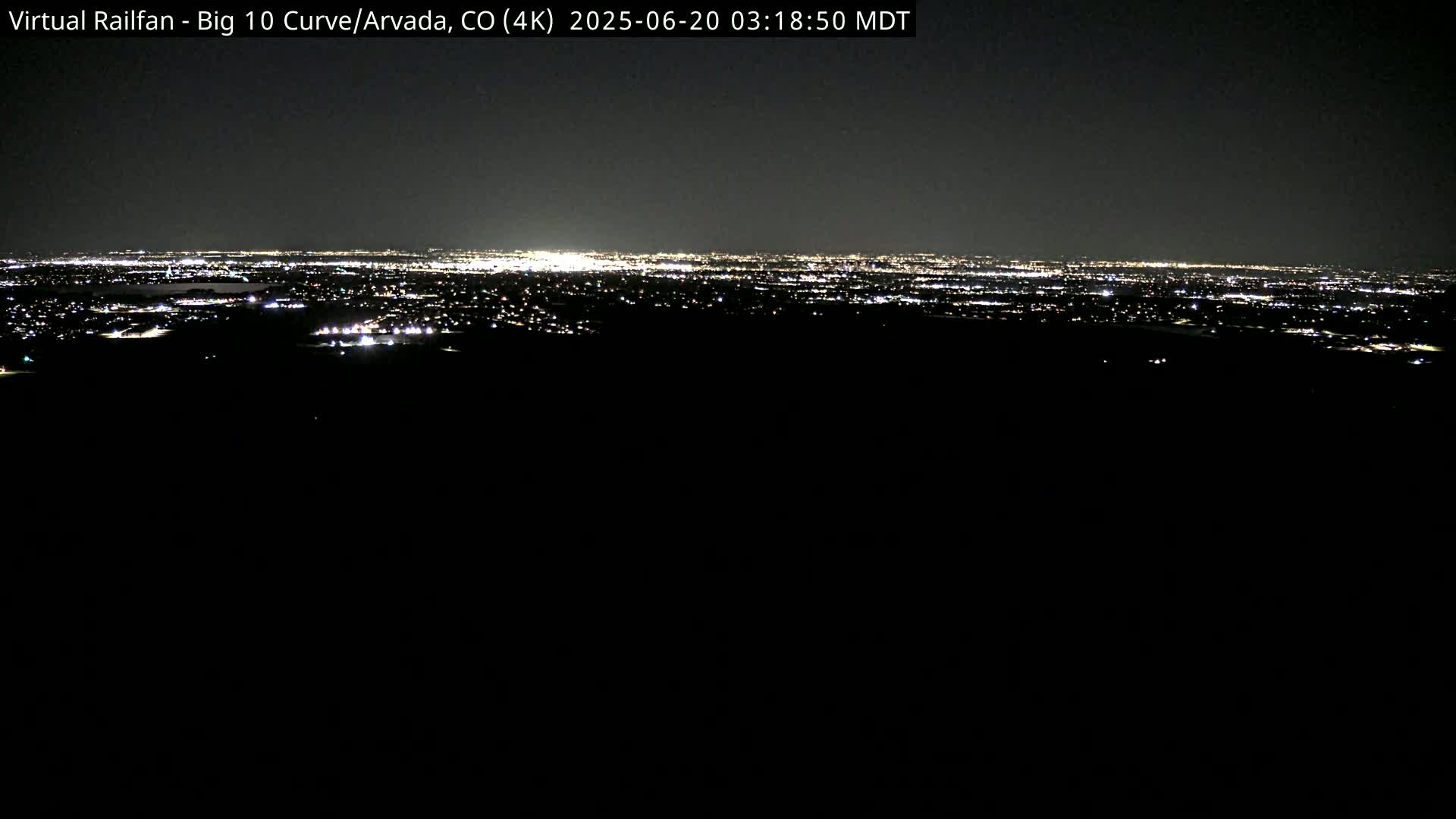 A nighttime, long-distance view of a city skyline illuminated by numerous lights.