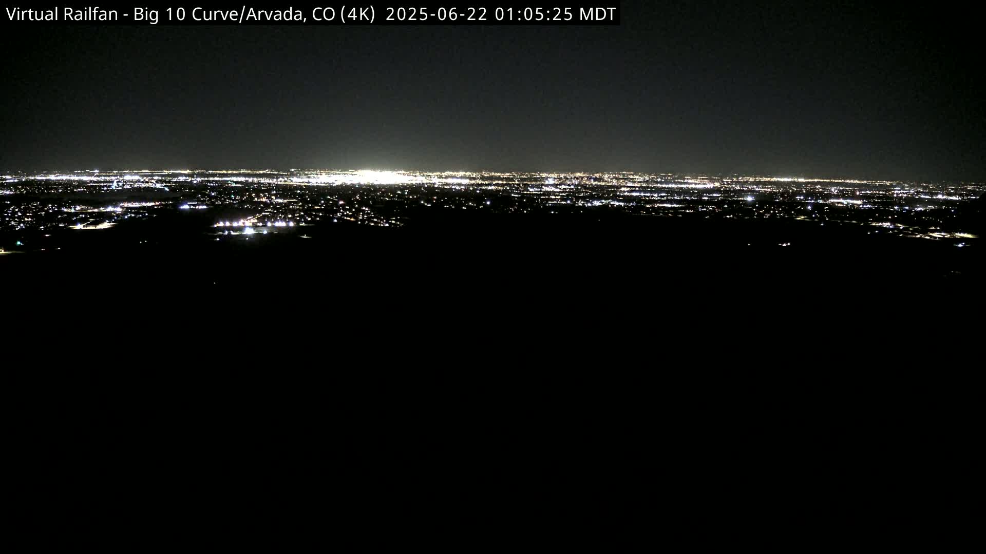 A nighttime, long-range view of a city's lights spread across a dark landscape.