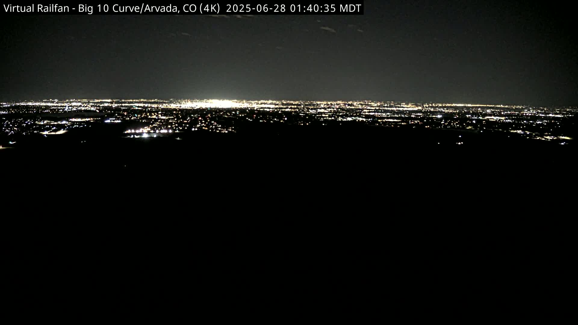 A nighttime, long-range view of a city's lights spread across a dark landscape.