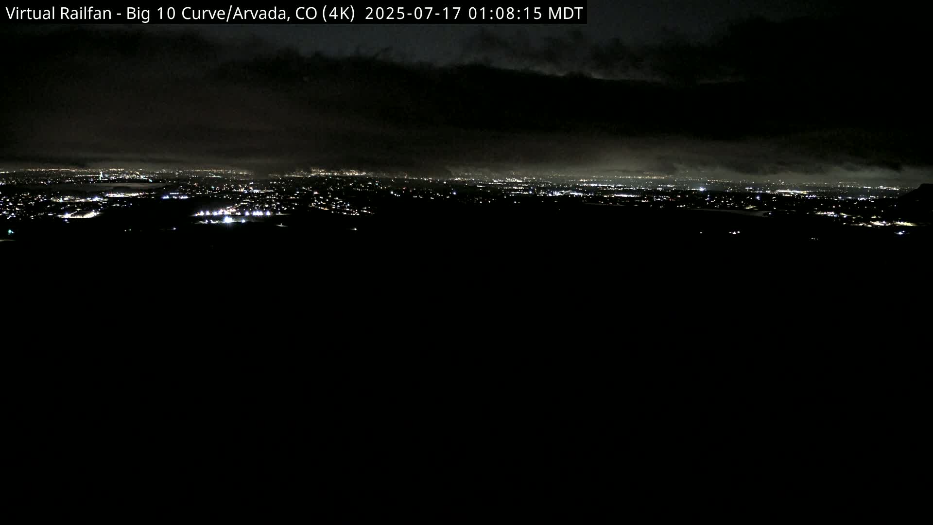 A nighttime view of a city skyline under a cloudy sky.