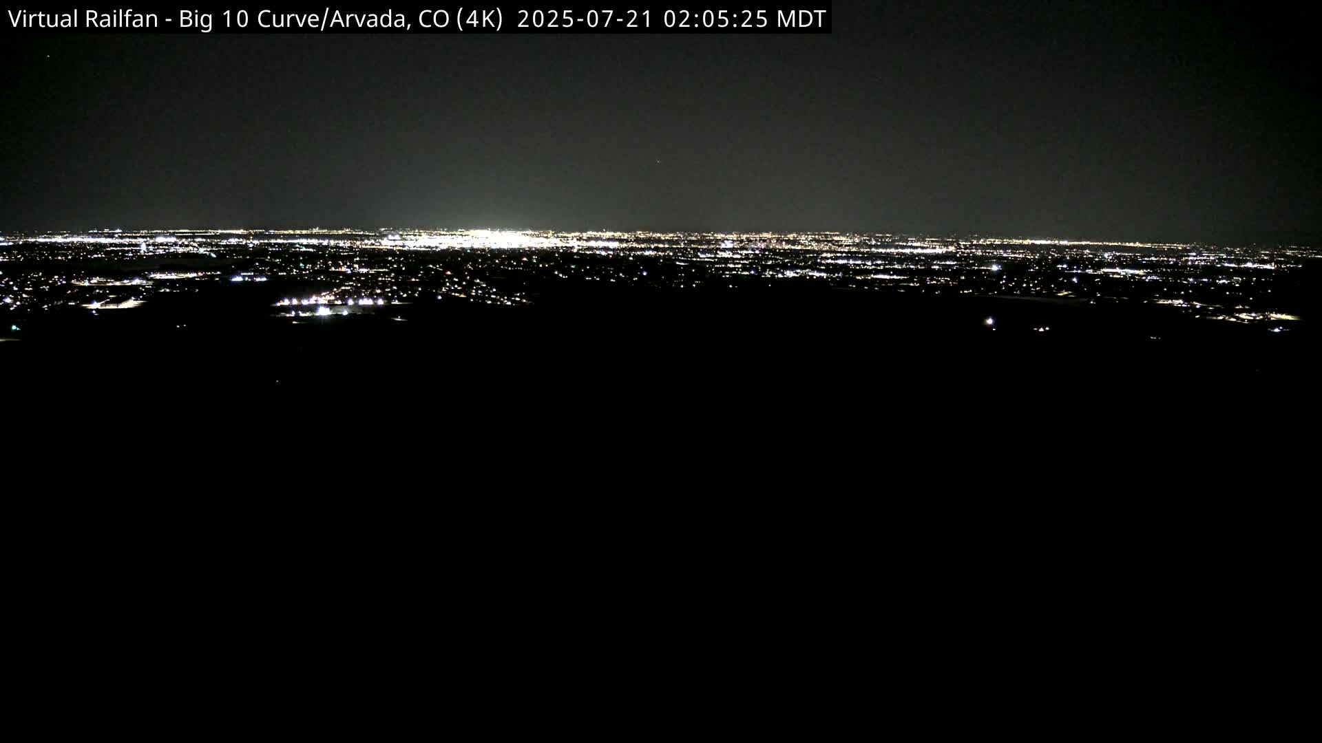 A nighttime, long-range view of a city's lights spread across a dark landscape.