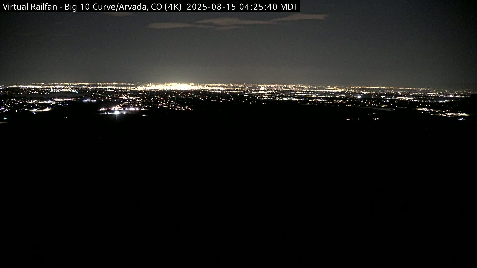 A nighttime long shot reveals a distant city skyline illuminated by lights under a dark sky.
