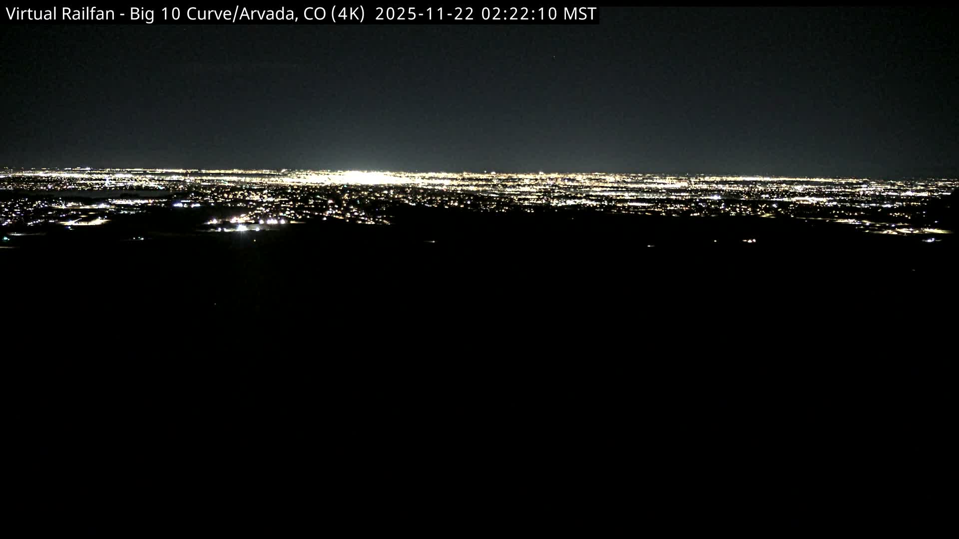 A sprawling city is visible in the distance, illuminated by countless lights under a clear, dark night sky.