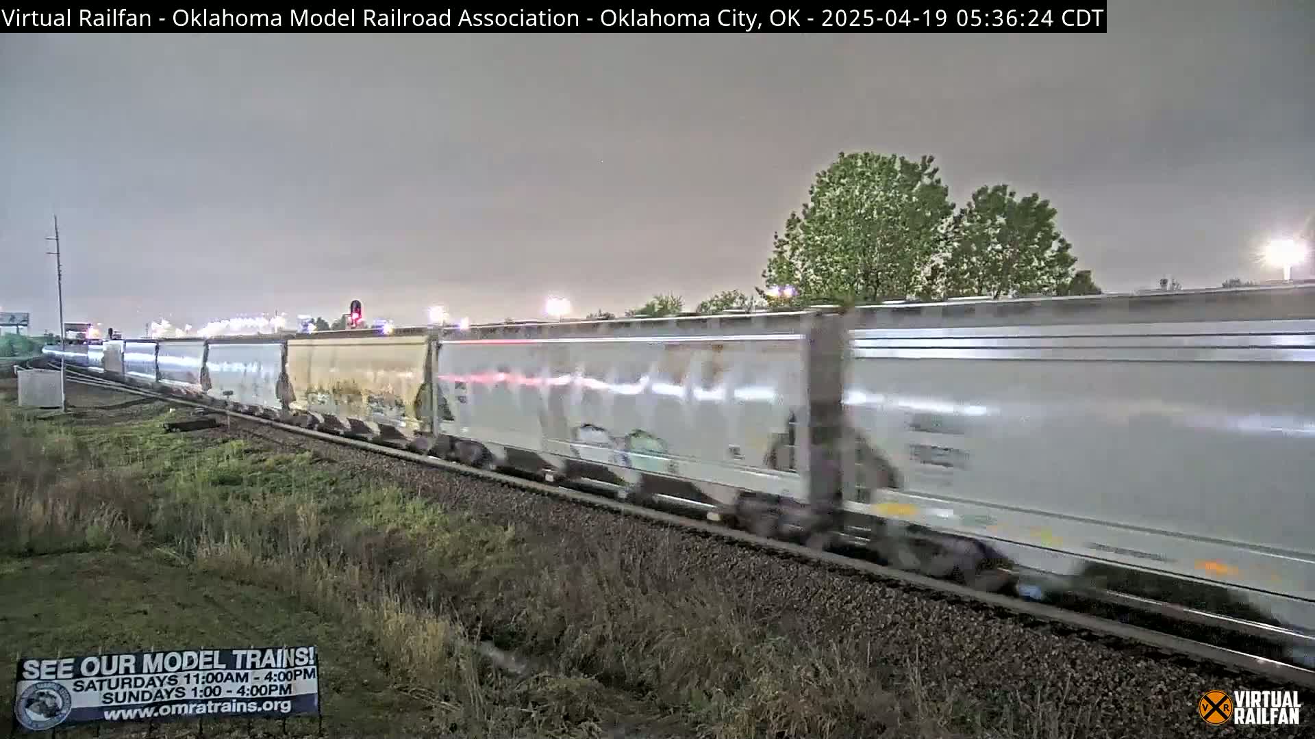 A long freight train moves past under a dark, overcast sky.