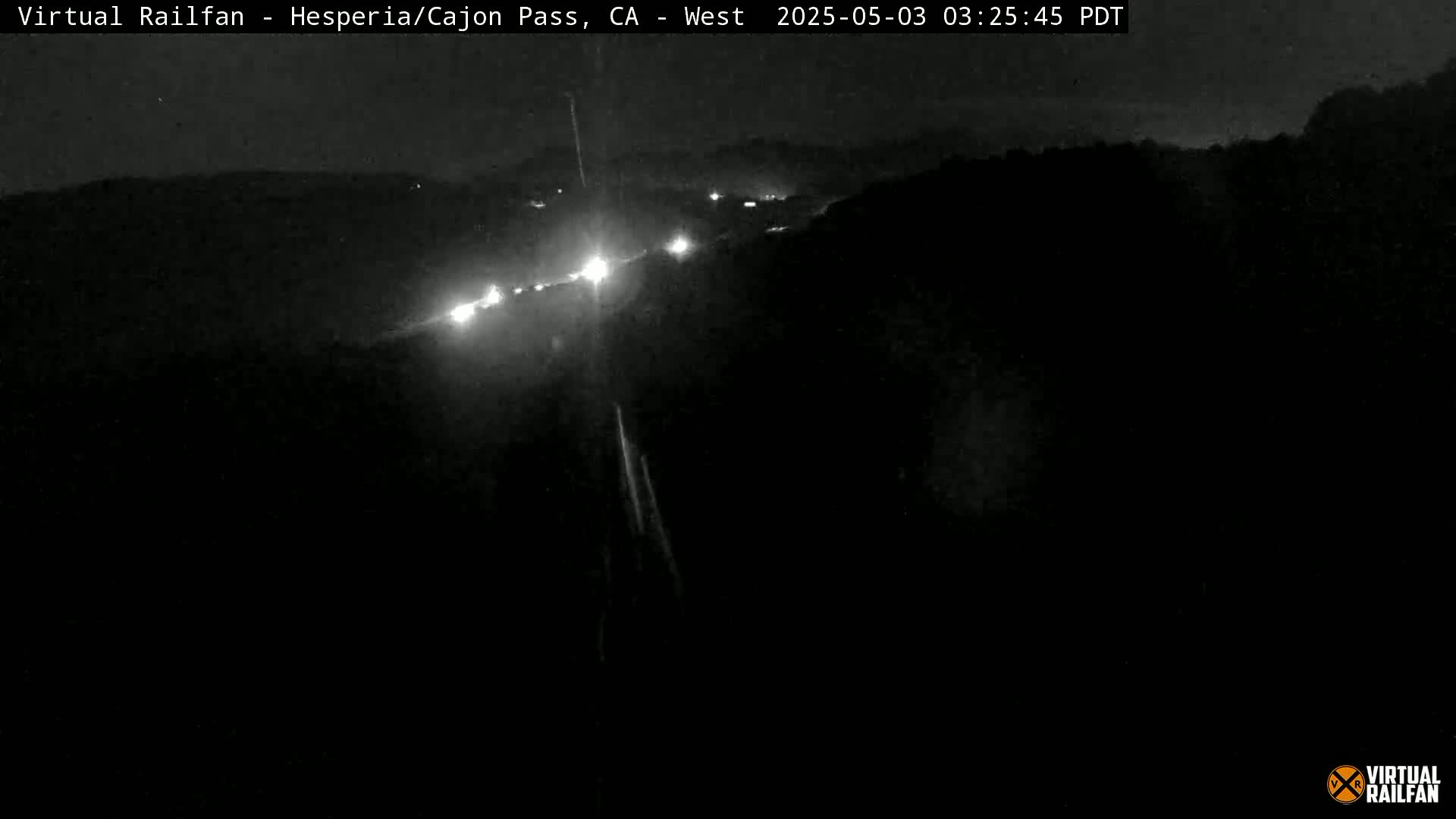 A nighttime, long-distance view of a highway with sparse vehicle headlights visible in the distance.