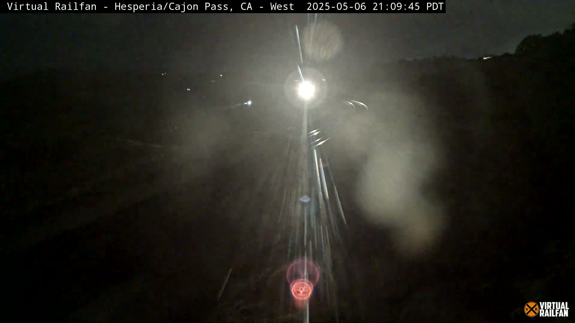 A nighttime, hazy view of bright headlights approaching on a dark roadway.
