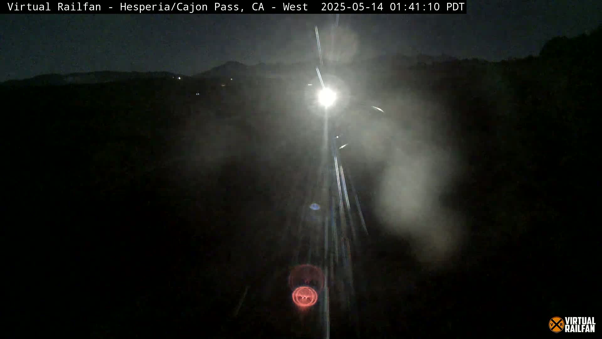 A nighttime view of a train moving forward through a foggy landscape.