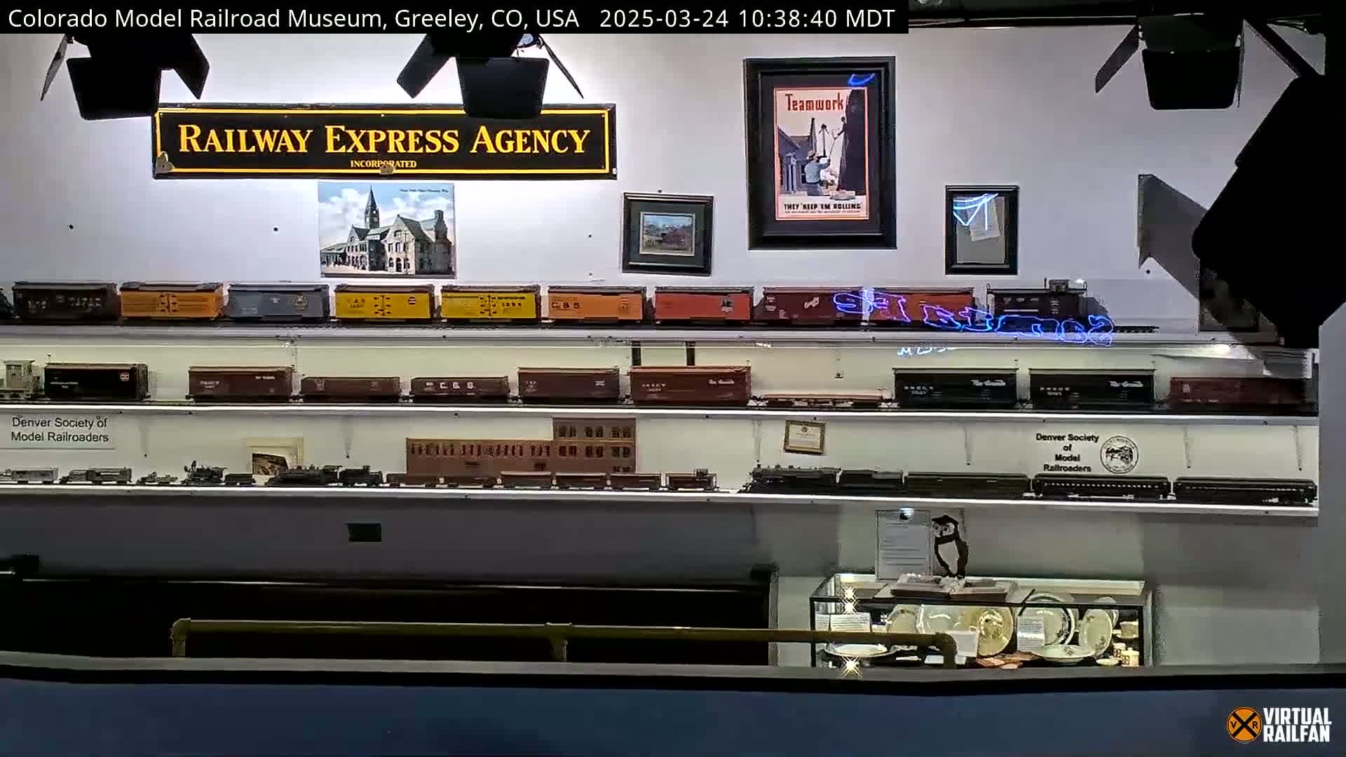 Many model trains are displayed on shelves in a museum setting.