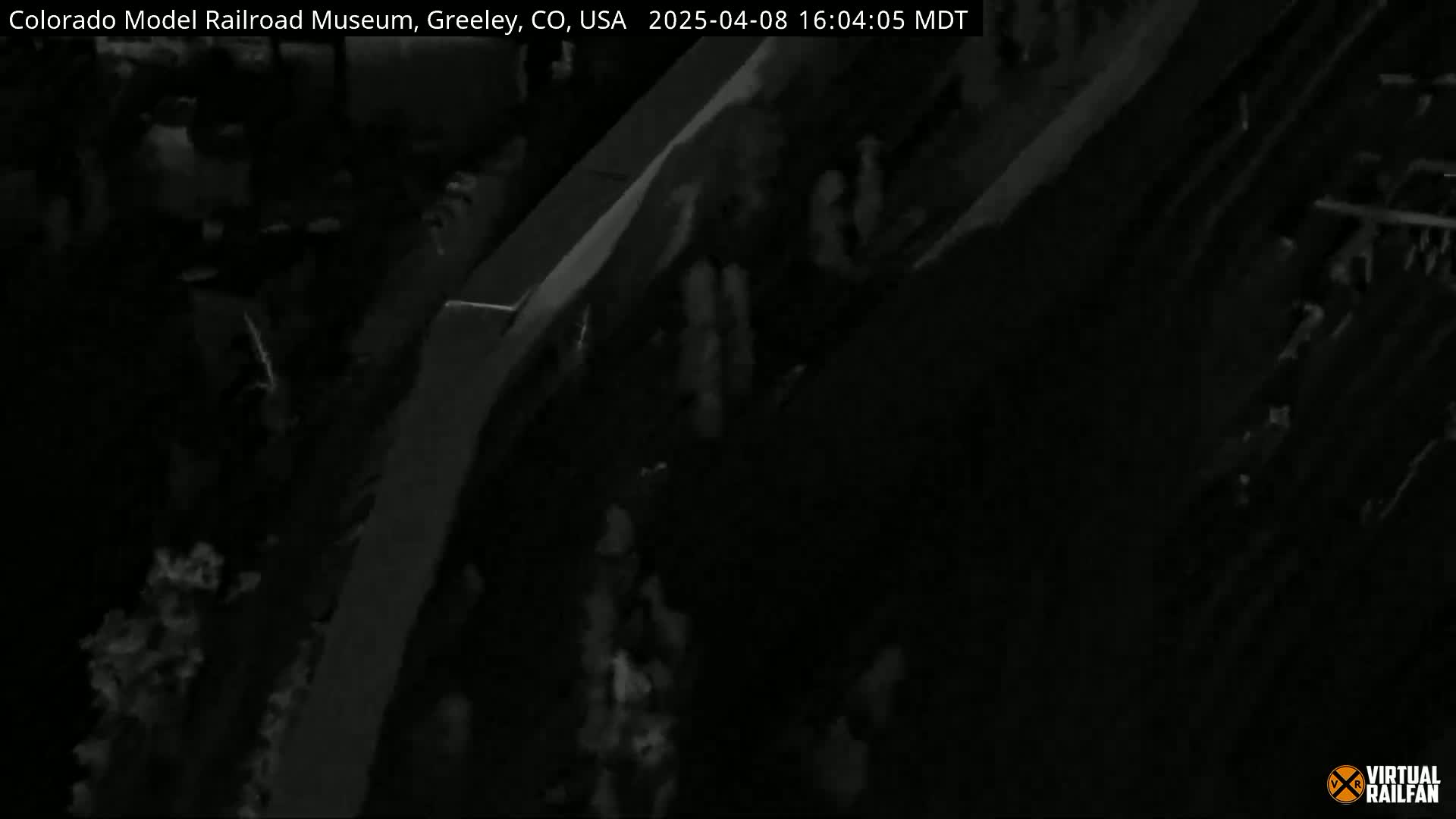 A low-light, nighttime image shows a dark, possibly outdoor, scene with indistinct shapes suggesting people and structures.