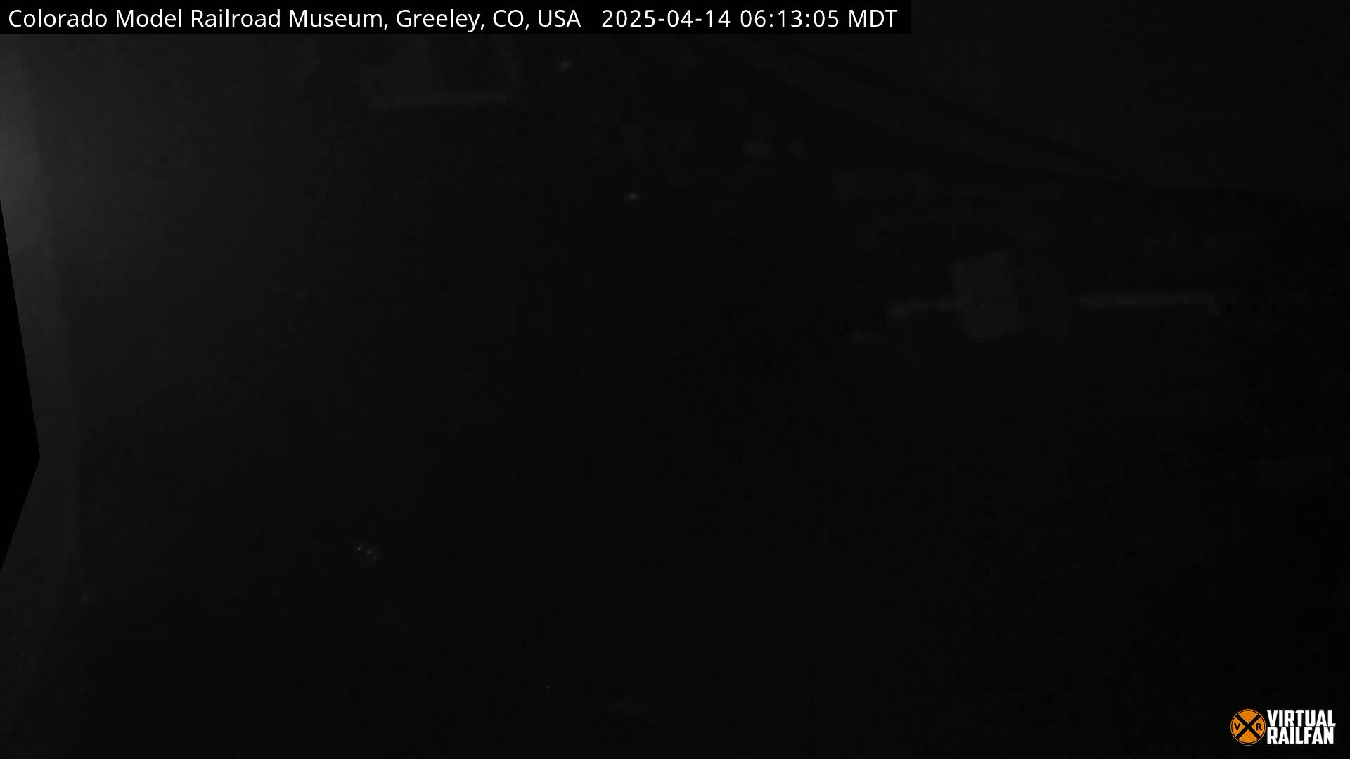A very dark, nighttime image shows a mostly black scene with a few faint, indistinct light sources.