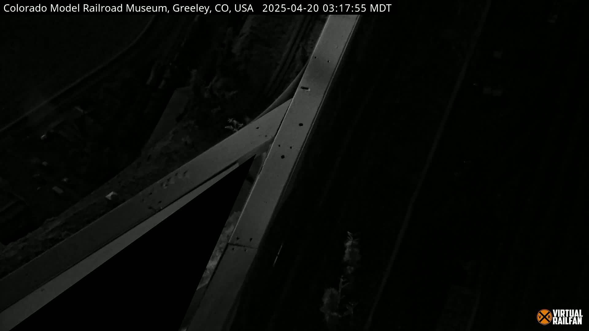 A nighttime, overhead view shows intersecting gray concrete structures, possibly roadways or railroad tracks.