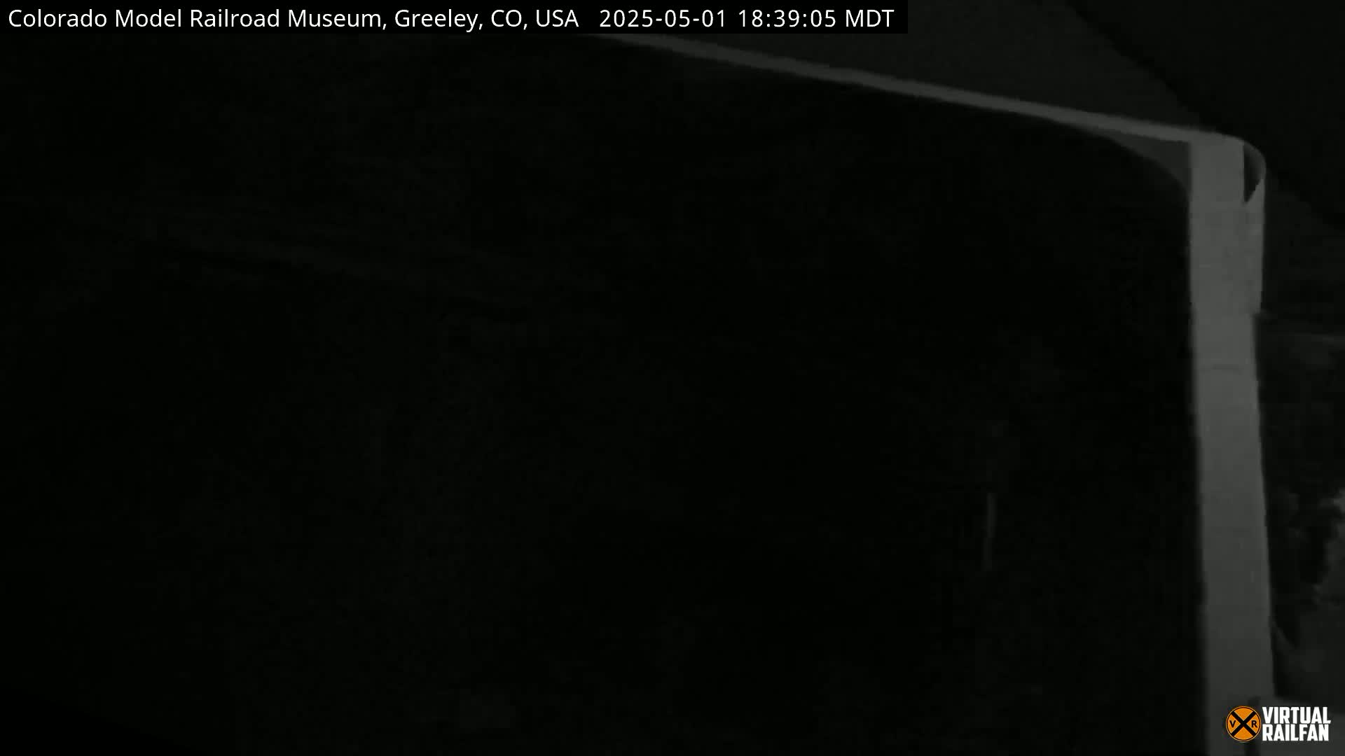 A nearly completely dark image shows a sliver of a light-colored object in the upper right corner, possibly taken at night.