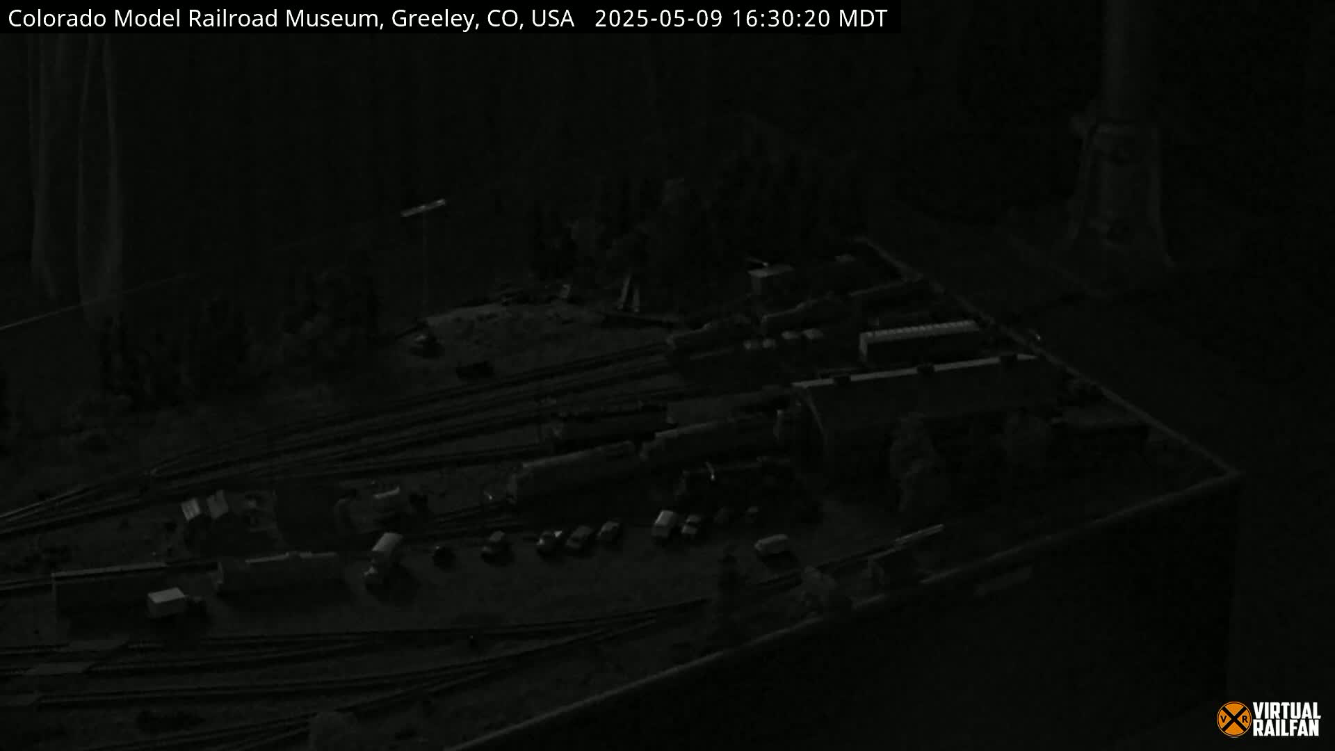 A dimly lit model train set is displayed on a dark surface.