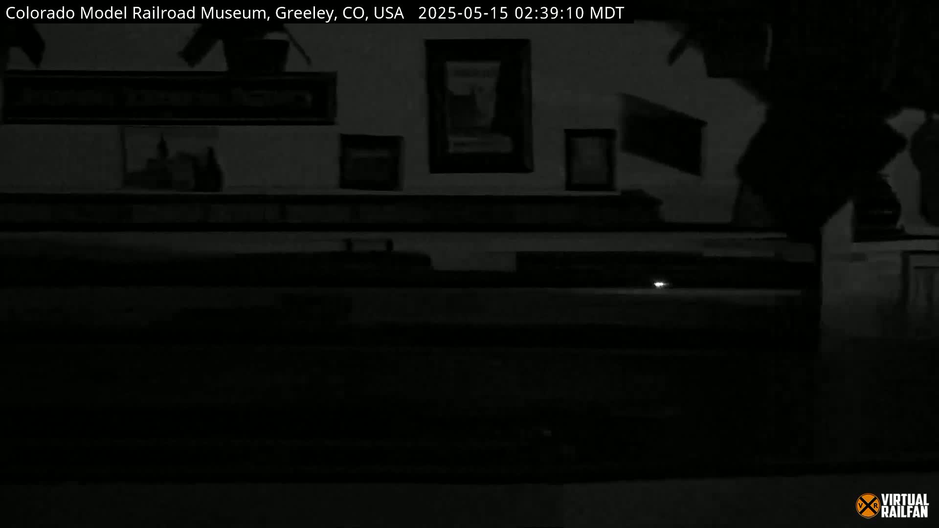A dimly lit interior space shows framed pictures on a wall above a dark counter.