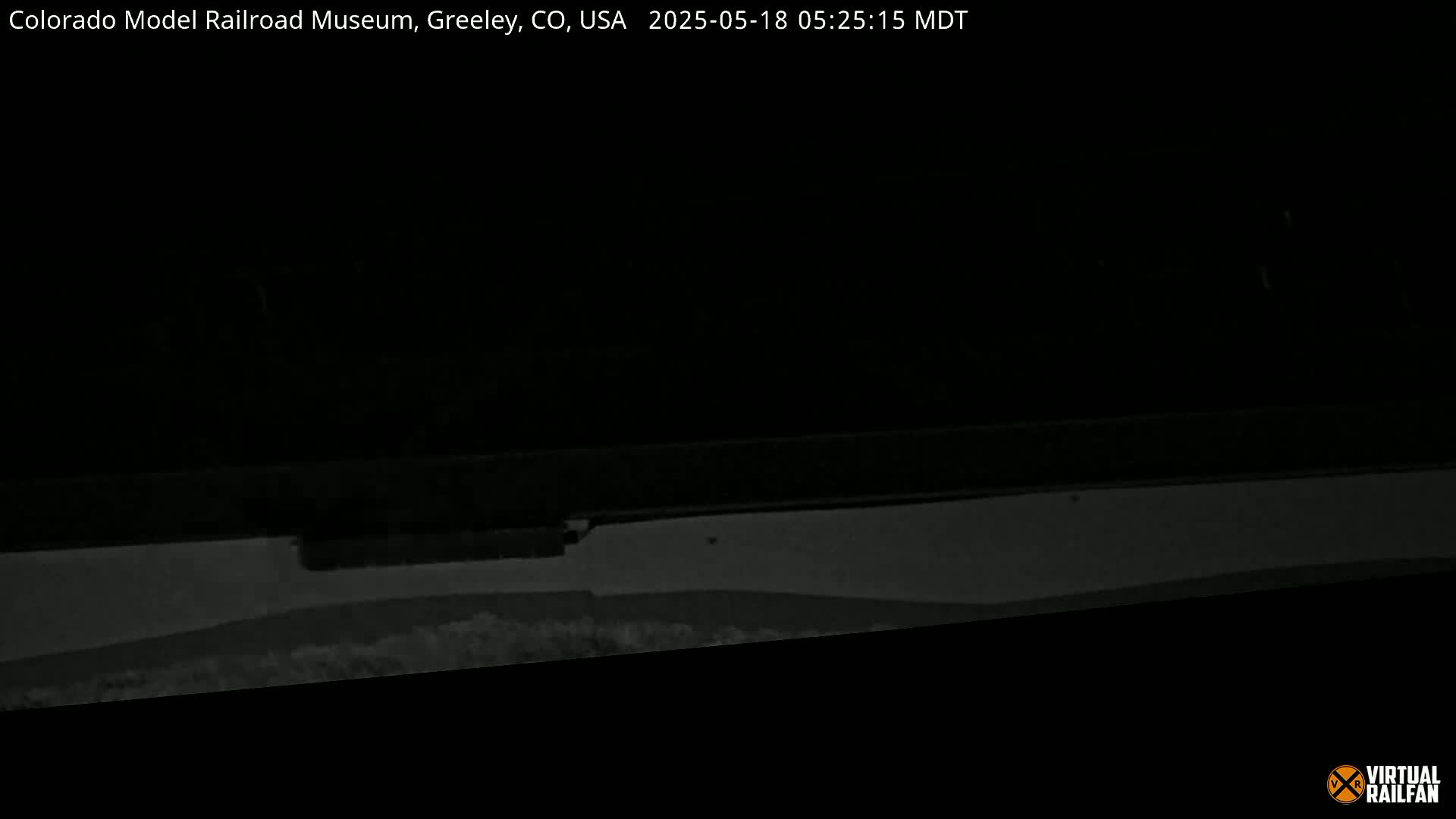 A low-light, nighttime image shows a dark, mostly featureless scene with a light-colored horizontal surface at the bottom.