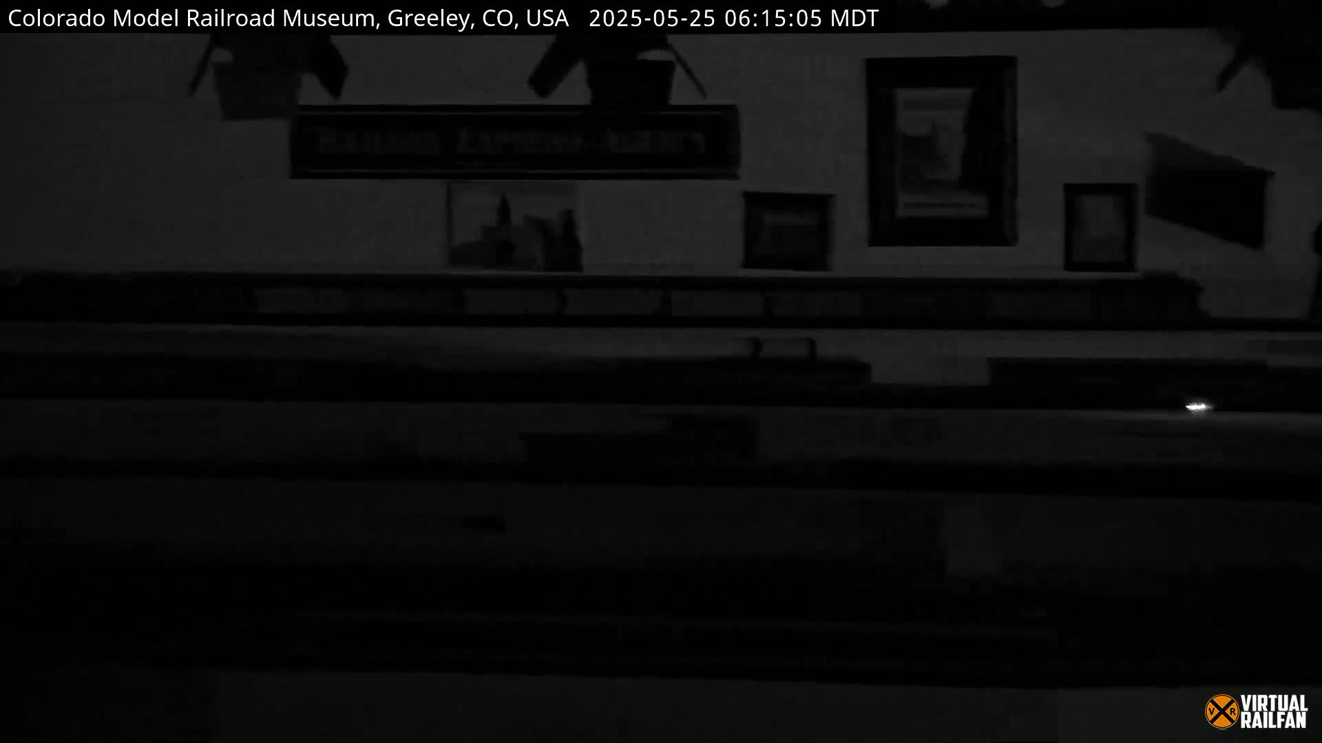 A dimly lit interior space with framed pictures on the wall and a low light source visible near the bottom.