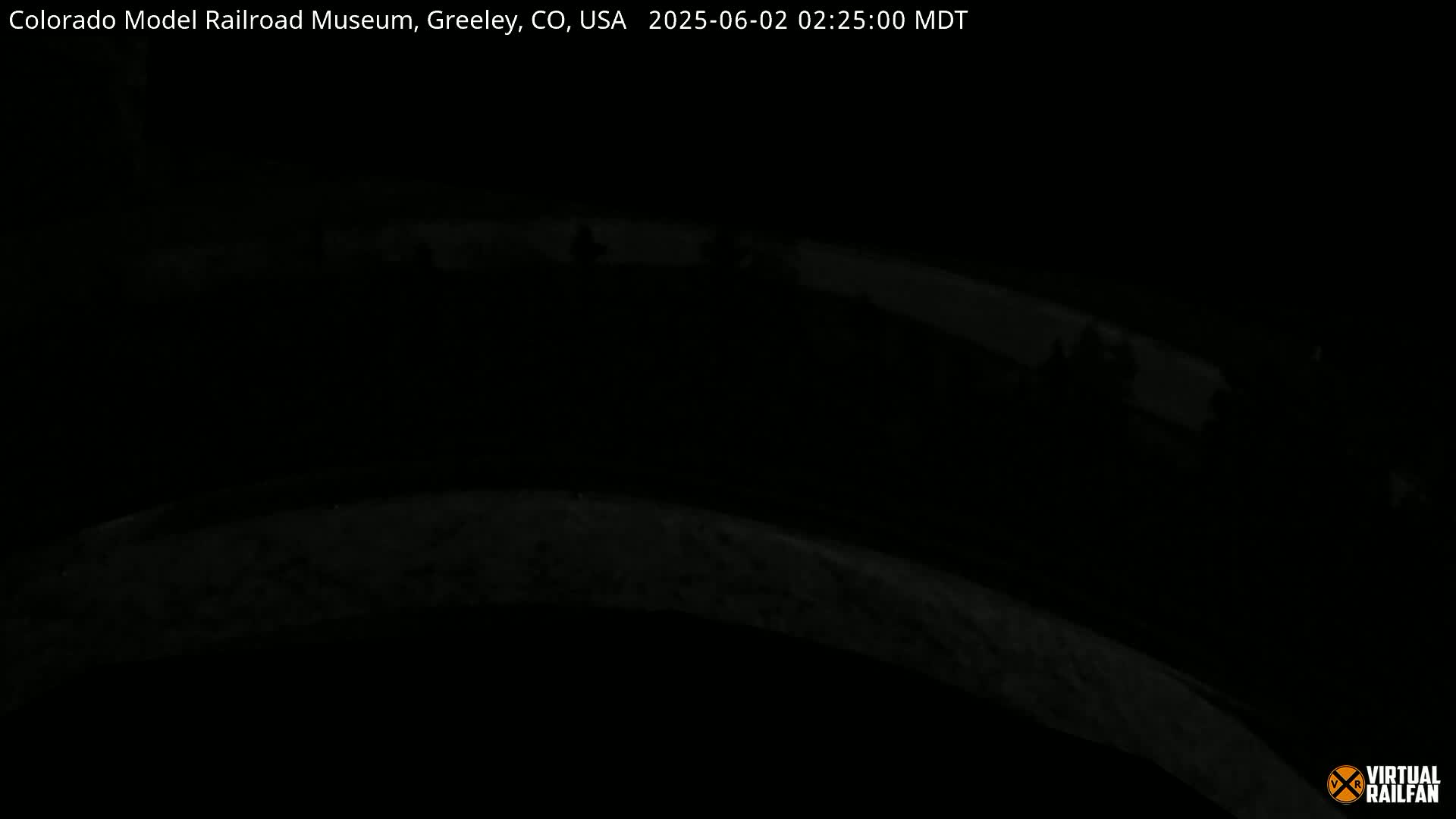 A nighttime, dark view of a curved roadway or path.