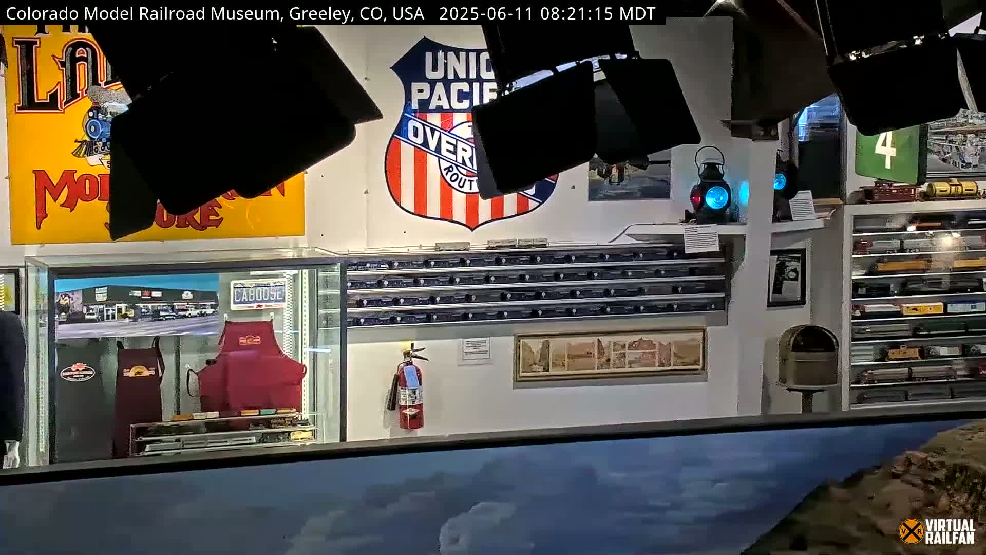 An indoor museum displays various railroad memorabilia, including signs, model trains, and railroad artifacts, under artificial lighting.