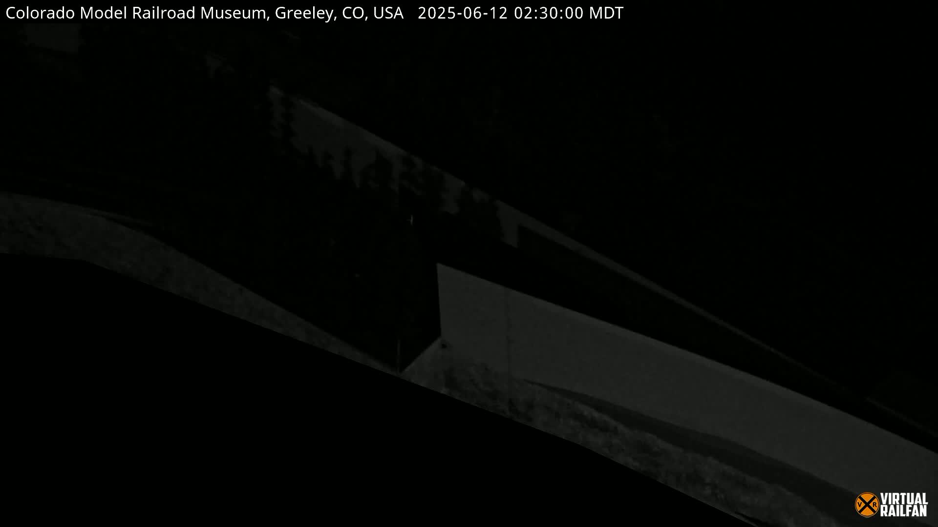 A low-light, nighttime image shows a dark, indistinct structure, possibly a building or wall.