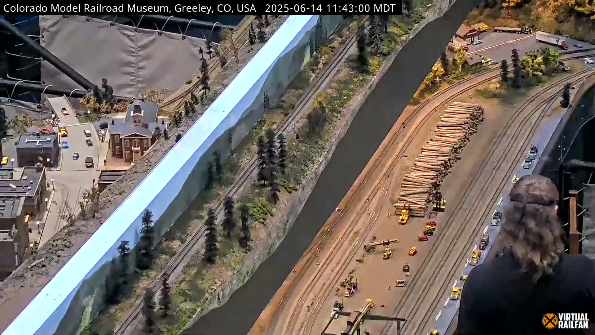 A large model railroad layout depicting a town, a river, and a logging operation.