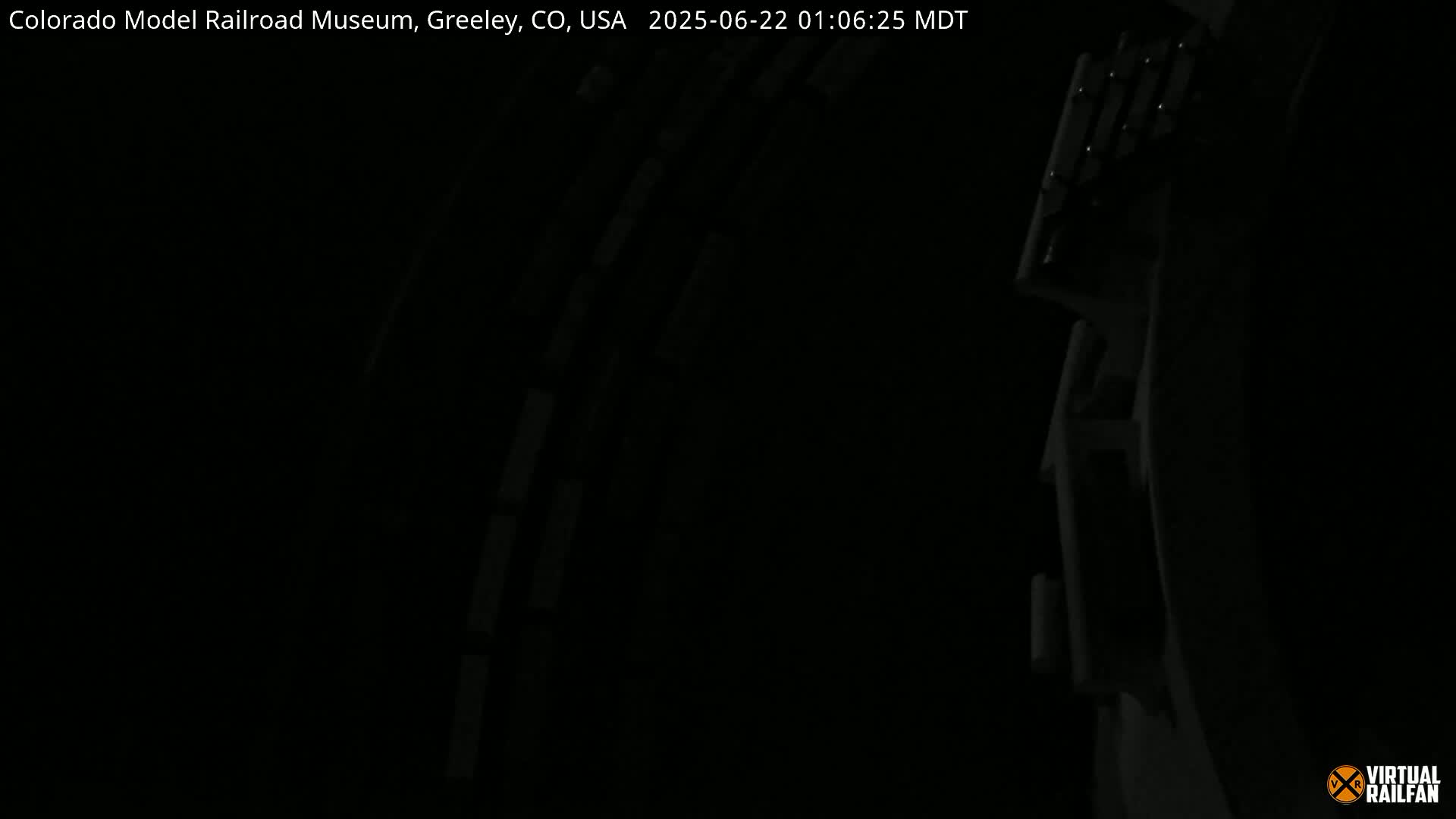 A dark, possibly indoor, scene shows a partially visible structure with repeating horizontal lines.