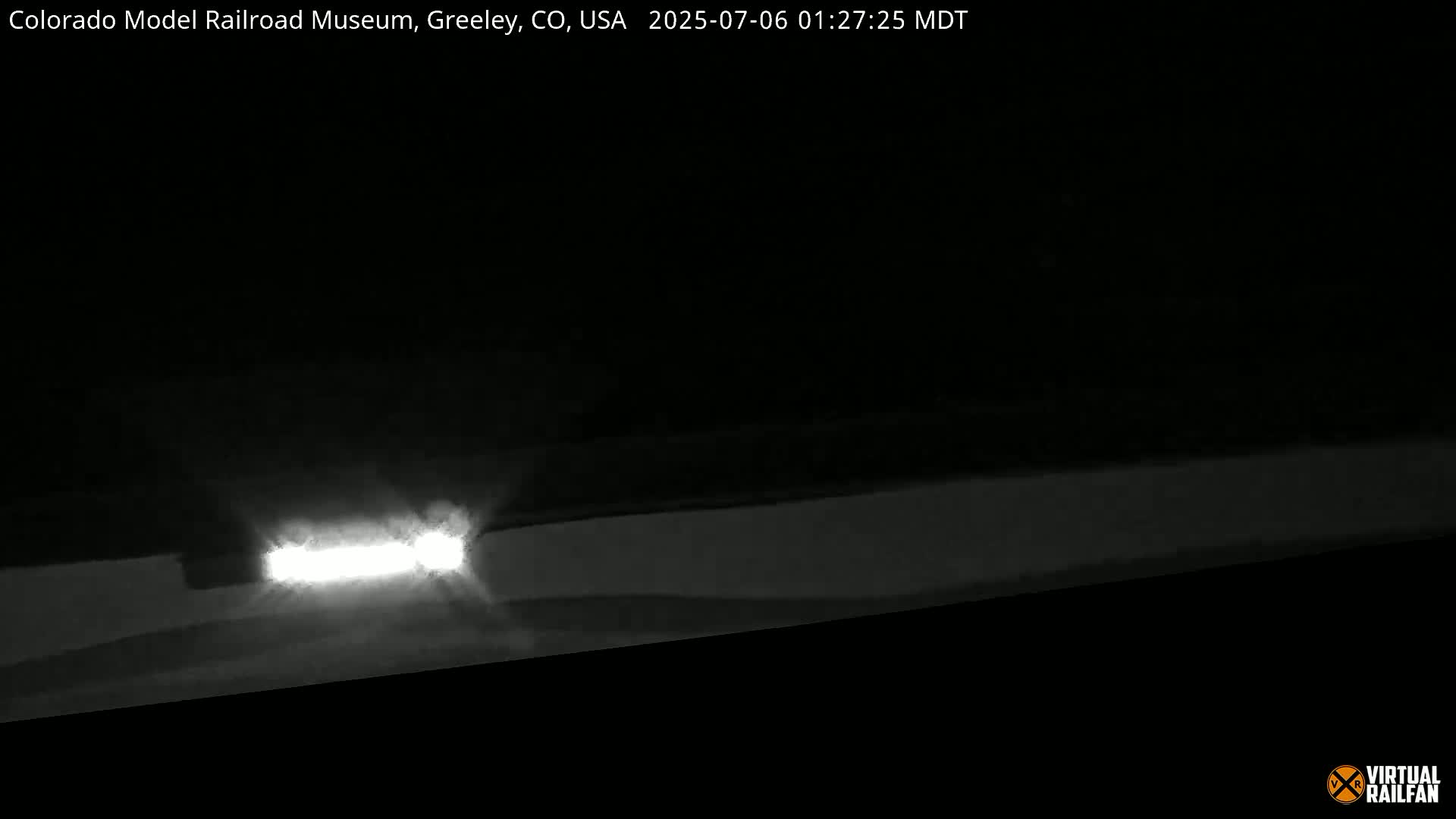 Headlights of a vehicle illuminate a dark, nighttime scene.