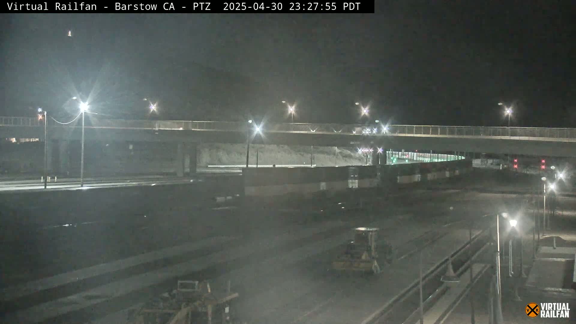 A nighttime view of a highway overpass and surrounding roadways, with some construction or maintenance equipment visible.